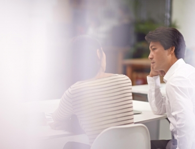 Zwei Personen, die an einem Tisch ein Feedbackgespräch führen