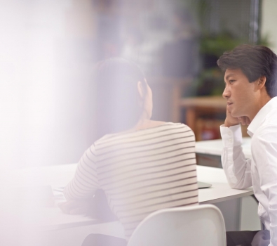Zwei Personen, die an einem Tisch ein Feedbackgespräch führen